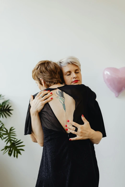 two women hugging each other in a room, a tattoo, pexels contest winner, xqc, carole feuerman, back arched, sydney hanson