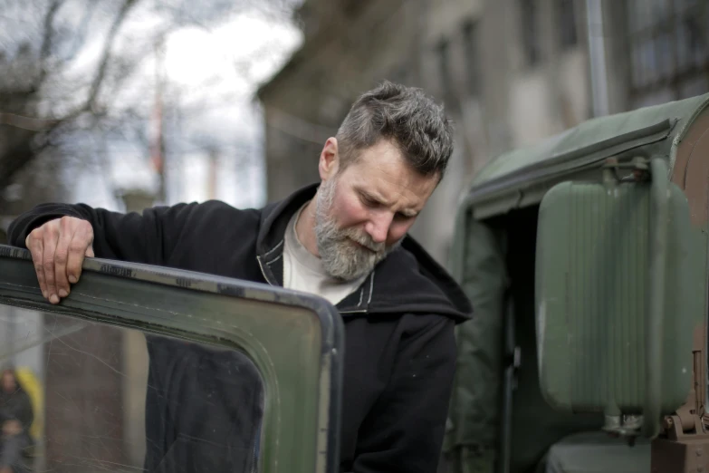 a man leaning on the door of a military vehicle, pexels contest winner, renaissance, gray beard, repairing the other one, hgtv, looking from shoulder