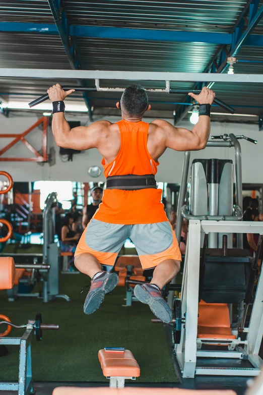 a man doing pull ups in a gym, by Robbie Trevino, thailand, orange grey white, instagram picture, bandoliers