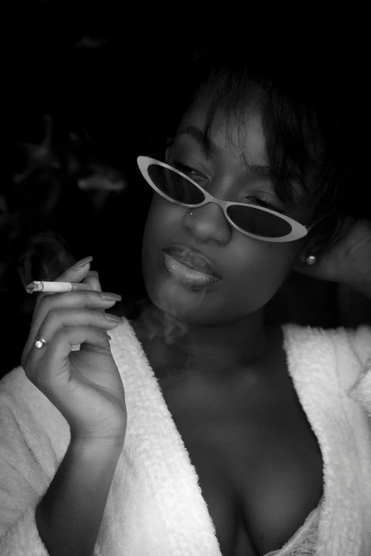 a black and white photo of a woman smoking a cigarette, inspired by Zelma Blakely, sza, wearing shades, taken in the late 2000s, african domme mistress