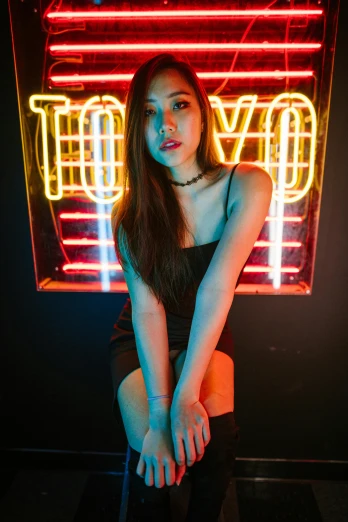 a woman sitting on a stool in front of a neon sign, by Robbie Trevino, trending on pexels, beautiful young asian woman, soft lighting from above, wearing a cropped black tank top, cinematic. by leng jun
