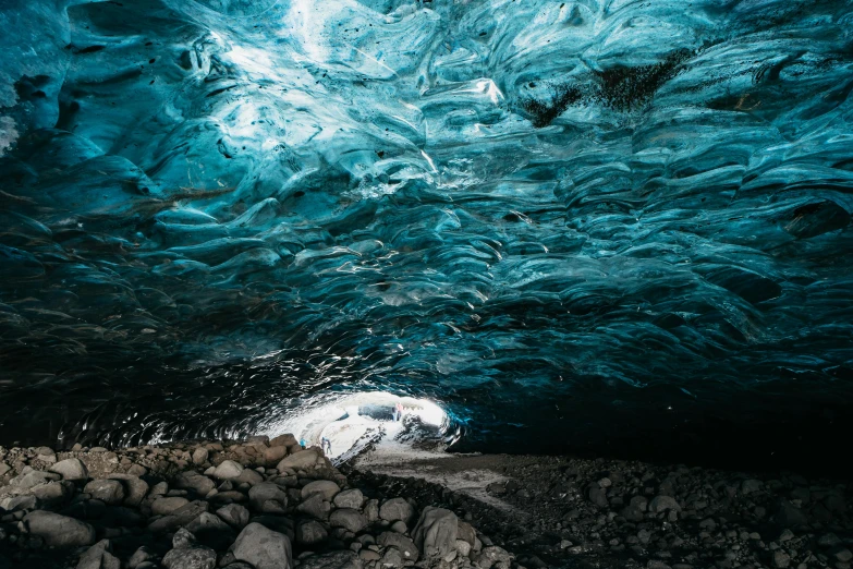 the inside of an ice cave with rocks and water, by Julia Pishtar, blue sand, inside of a car, swirling, black sand