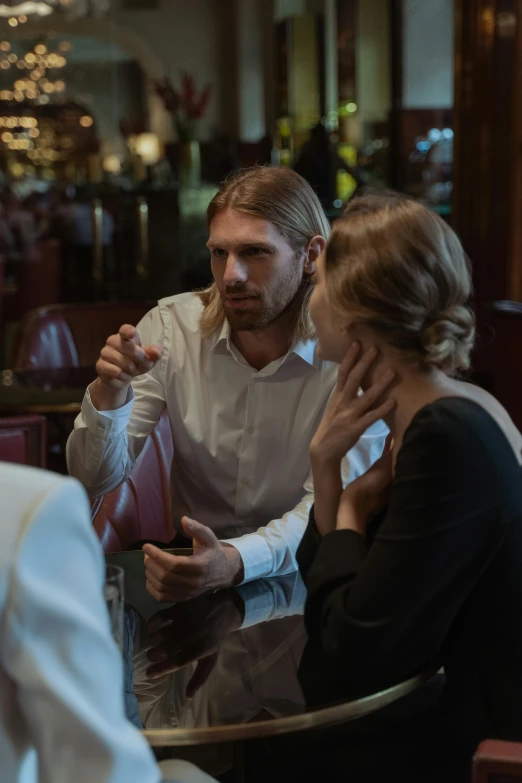 a group of people sitting around a table, intense flirting, blonde man, cinestill 800t 50mm eastmancolor, cinematic luts