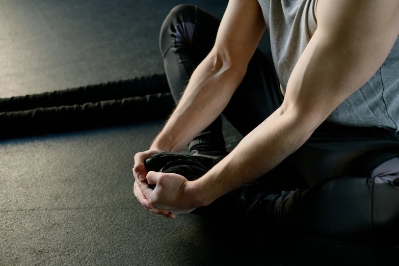 a man sitting on the floor in a gym, pexels contest winner, renaissance, wrapped arms, background image, lachlan bailey, middle close up composition