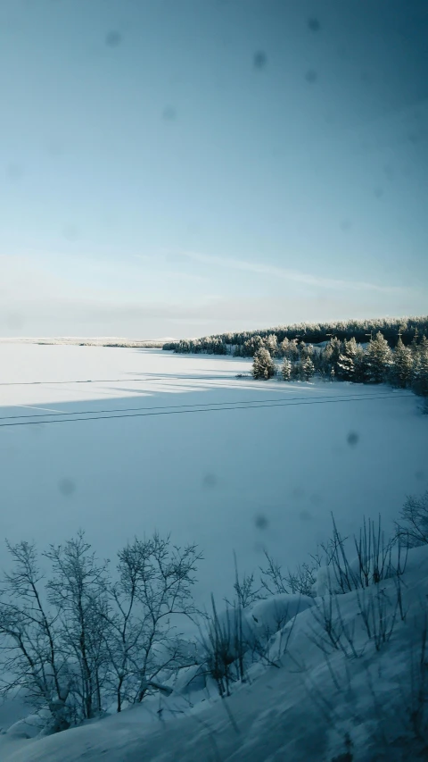 a large body of water sitting on top of a snow covered field, inspired by Eero Järnefelt, pexels contest winner, hurufiyya, train window, next to farm fields and trees, minn