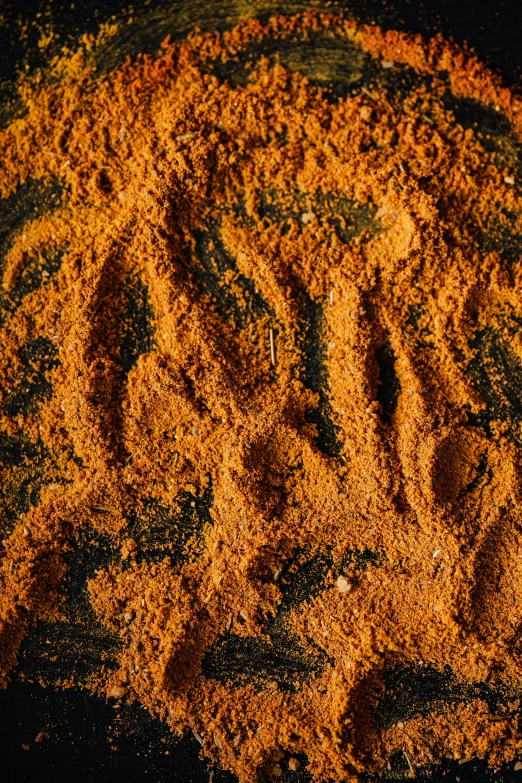 a pile of sand sitting on top of a black surface, vibrant patterns, spices, detailed product image, vibrant orange