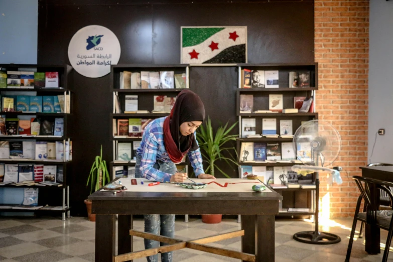 a woman standing at a table writing on a piece of paper, inspired by Bouchta El Hayani, infinite library, damascus, official store photo, on a canva