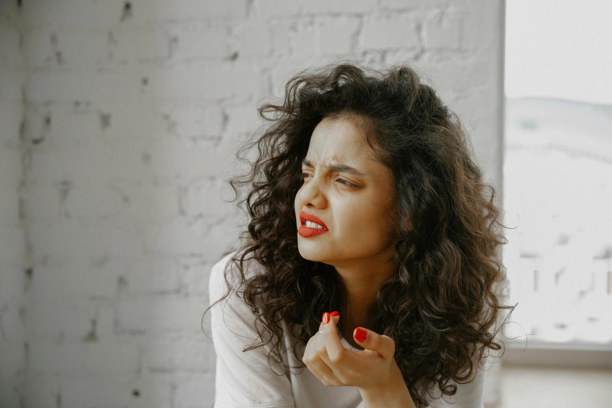 a woman brushing her teeth in front of a window, an album cover, trending on pexels, antipodeans, curly dark hair, angry and pointing, vibrent red lipstick, sexy pudica pose gesture