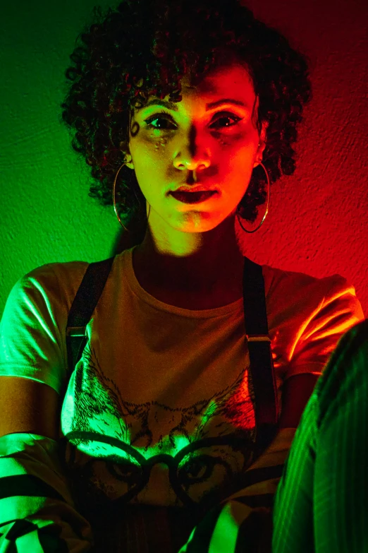 a woman sitting in front of a red and green wall, inspired by Nan Goldin, afrofuturism, colored lights, ashteroth, headshot, medium shot of two characters