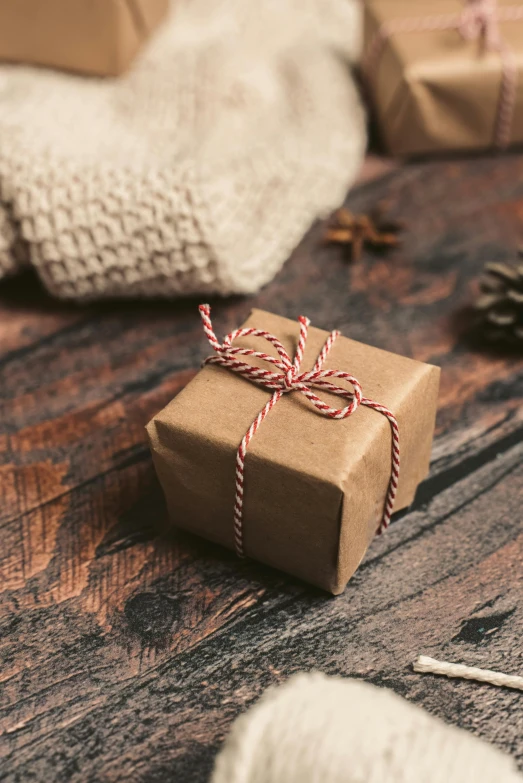 a gift wrapped in brown paper sitting on top of a wooden table, square, thumbnail, brown sweater, uncrop