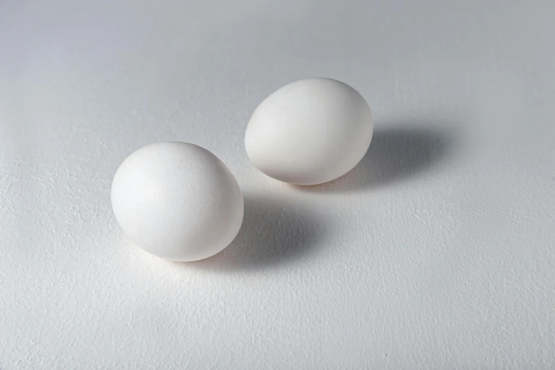 two white eggs sitting on top of a white surface, inspired by Vija Celmins, unsplash, snacks, birds eye, white sleeves, smooth light shading