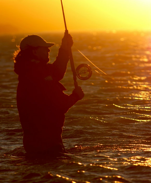 a man standing in the water holding a fishing rod, by Jan Tengnagel, pexels contest winner, hurufiyya, warm glow, flight, manly, rainbow