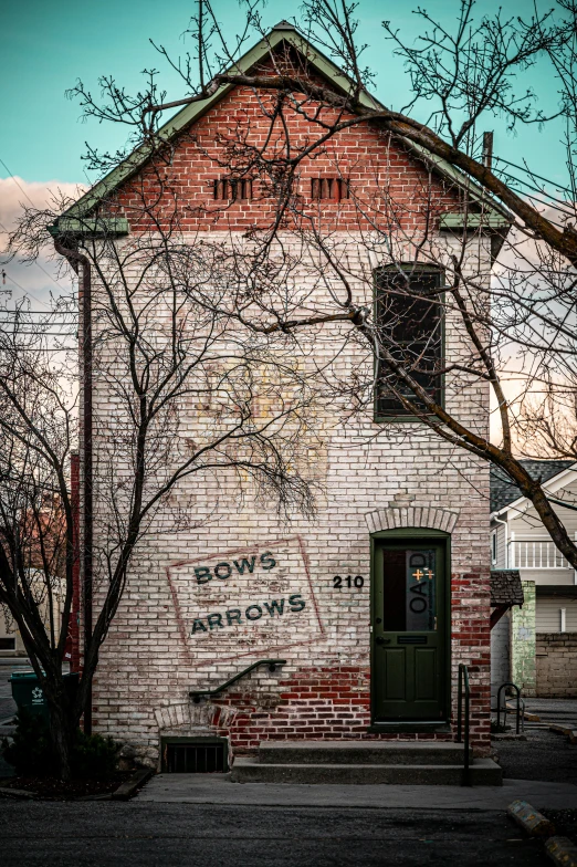 a brick building with a tree in front of it, by Michael Andrews, pexels contest winner, street art, long bow and arrows, old pawn shop, willows, advertising photo