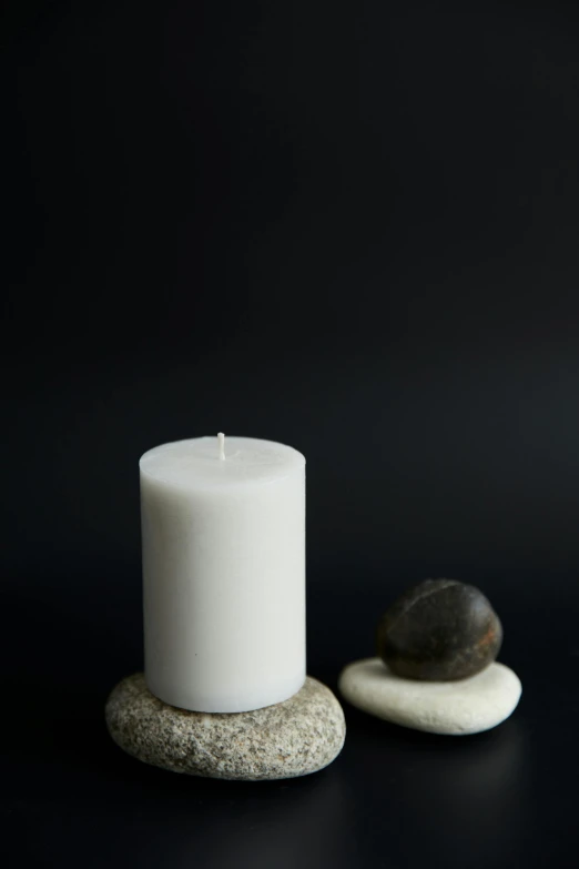 a candle and some rocks on a black surface, soft white rubber, 80mm, pillar, small scale