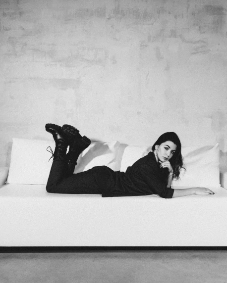 a woman laying on top of a white couch, a black and white photo, by Lucia Peka, unsplash, total black outfit, miranda cosgrove, bae suzy, androgyny