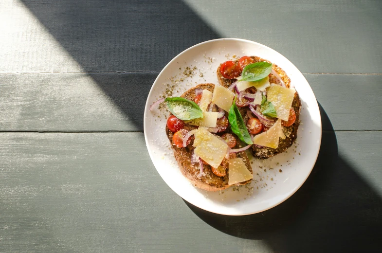 a close up of a plate of food on a table, unsplash, renaissance, brown bread with sliced salo, background image, basil, cheesy