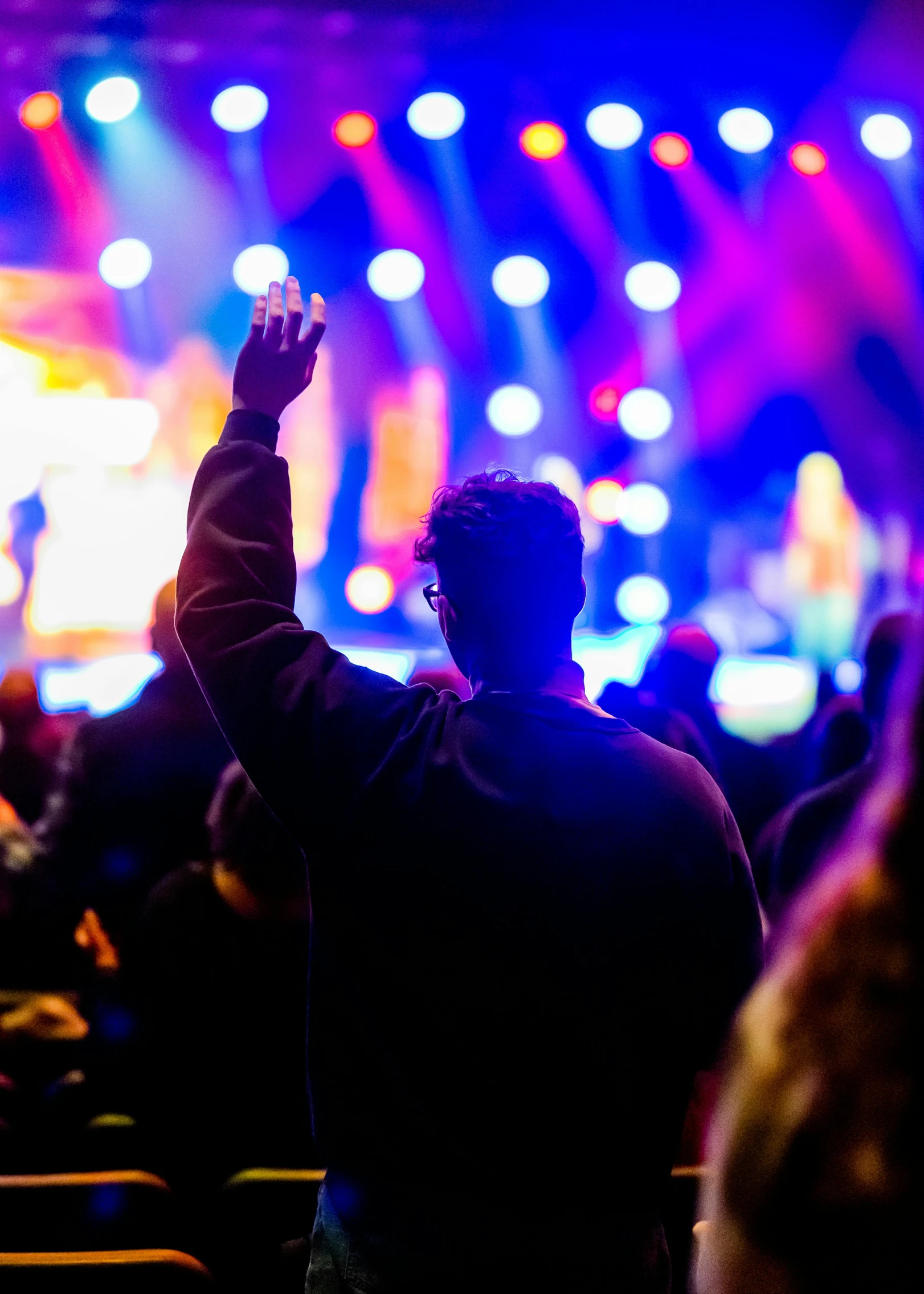 a man standing in front of a crowd at a concert, pexels, holding a holy symbol, avatar image, sports photo, facing away