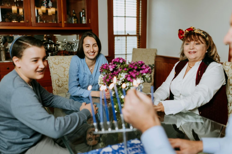 a group of people sitting around a table with candles