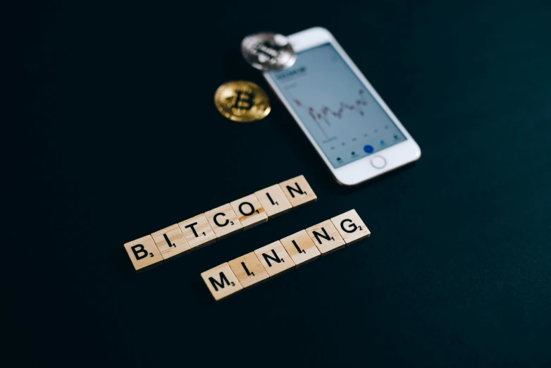 a cell phone sitting on top of a table next to a block that says bitcoin, trending on pexels, underground mine, avatar image, miners, profile pic