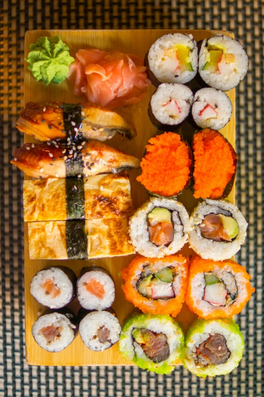a wooden cutting board topped with lots of sushi, belgium, birdseye view, kami