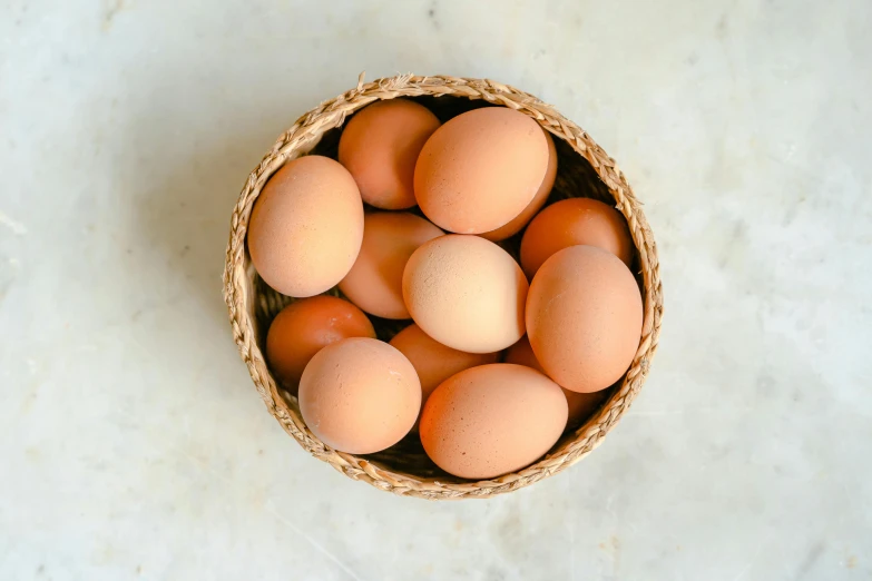 a basket filled with eggs sitting on top of a table, by Jessie Algie, trending on pexels, clay material, vanilla, top angle, natural soft rim light