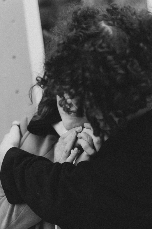 a black and white photo of a woman hugging a man, inspired by Nan Goldin, pexels, process art, black curly hair, doing a prayer, ! holding in his hand !, holding an epée