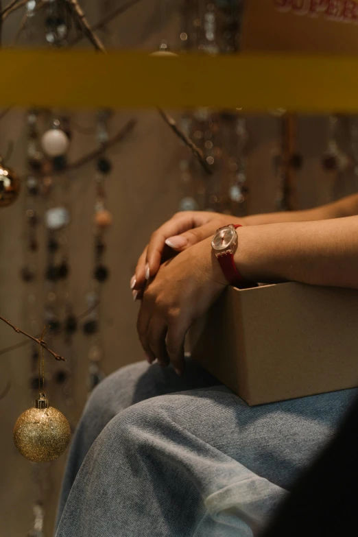 a close up of a person holding a box, by Julia Pishtar, trending on pexels, renaissance, sitting on santa, leather jewelry, thinking, watch photo