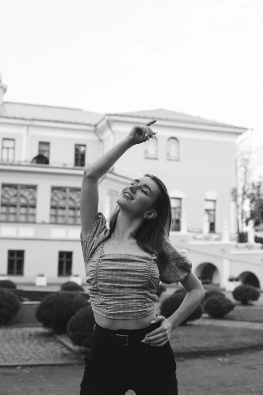 a black and white photo of a woman throwing a frisbee, a black and white photo, inspired by Alexey Venetsianov, pexels contest winner, aestheticism, in balcony of palace, pose(arms up + happy), holding a cigarette, in garden