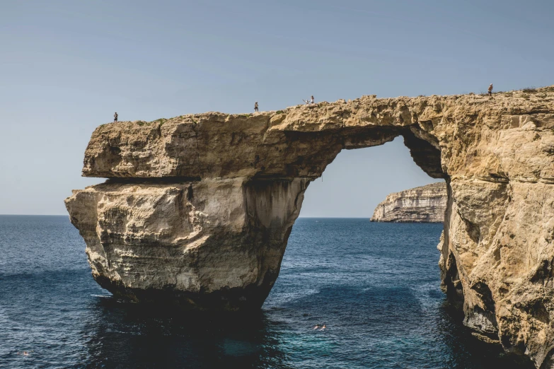 a large rock formation in the middle of the ocean, by Simon Marmion, pexels contest winner, dry archways, marsden, mediterranean island scenery, slide show