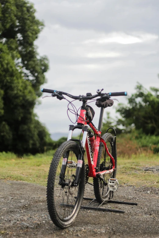 a bicycle parked on the side of a dirt road, riding a bike, crimson, frontal shot, ready to model