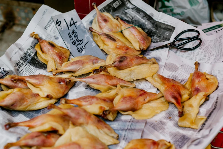 a pile of food sitting on top of a newspaper, a photo, trending on pexels, mingei, chicken feathers, hong kong, covered with organic flesh, rabbit ears