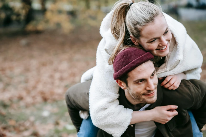 a man carrying a woman on his back, trending on pexels, during autumn, playful smile, beanie, digital image