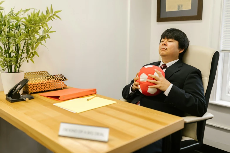 a man sitting at a desk holding a soccer ball, inspired by Ryuzaburo Umehara, sitting in dean's office, professional photo-n 3, professional cosplay, live action