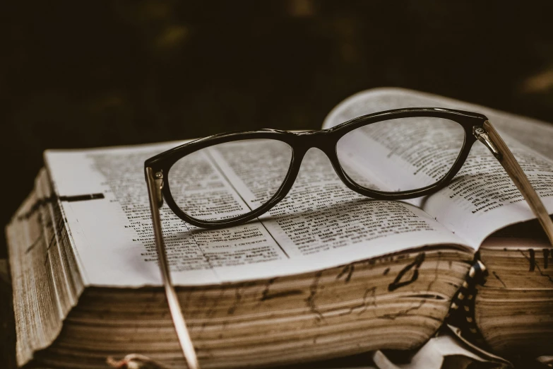 a pair of glasses sitting on top of an open book