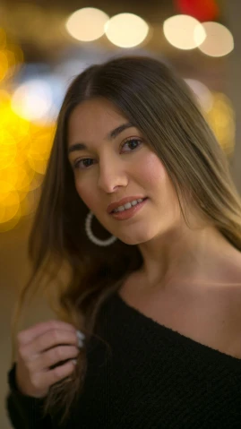a woman in a black top posing for a picture, by Robbie Trevino, pexels, warm glow from the lights, portrait sophie mudd, 8k 50mm iso 10, alexandria ocasio cortez
