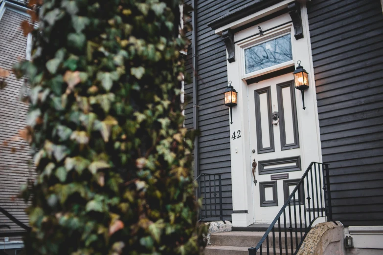 a black house with a white door and stairs, a photo, by Carey Morris, unsplash, arts and crafts movement, gas lighting, new england architecture, ivy's, profile image