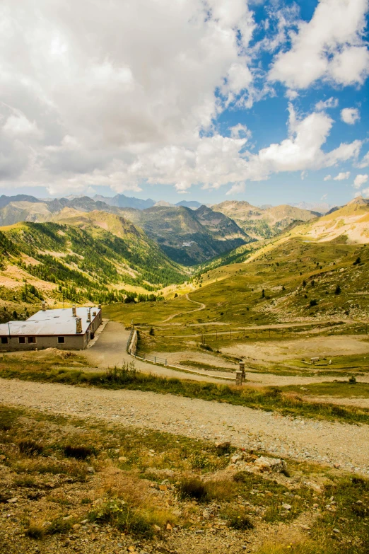 a dirt road running through a lush green valley, les nabis, alpine architecture, mining outpost, wide views, fan favorite