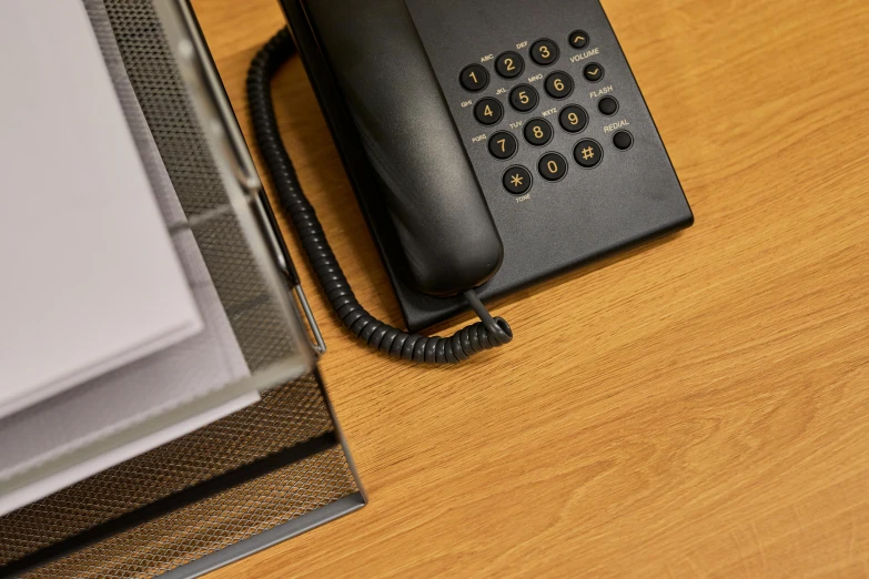 a black telephone sitting on top of a wooden desk, in an call centre office, birdseye view, realistic »