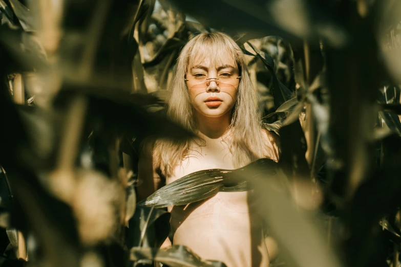 a woman standing in a field of corn, inspired by Elsa Bleda, trending on pexels, visual art, albino skin, with square glasses, chest covered with palm leaves, sydney sweeney