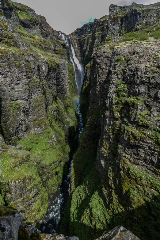 a man standing on top of a cliff next to a waterfall, by Hallsteinn Sigurðsson, hurufiyya, seen from straight above, panoramic shot, narrow passage, photograph taken in 2 0 2 0