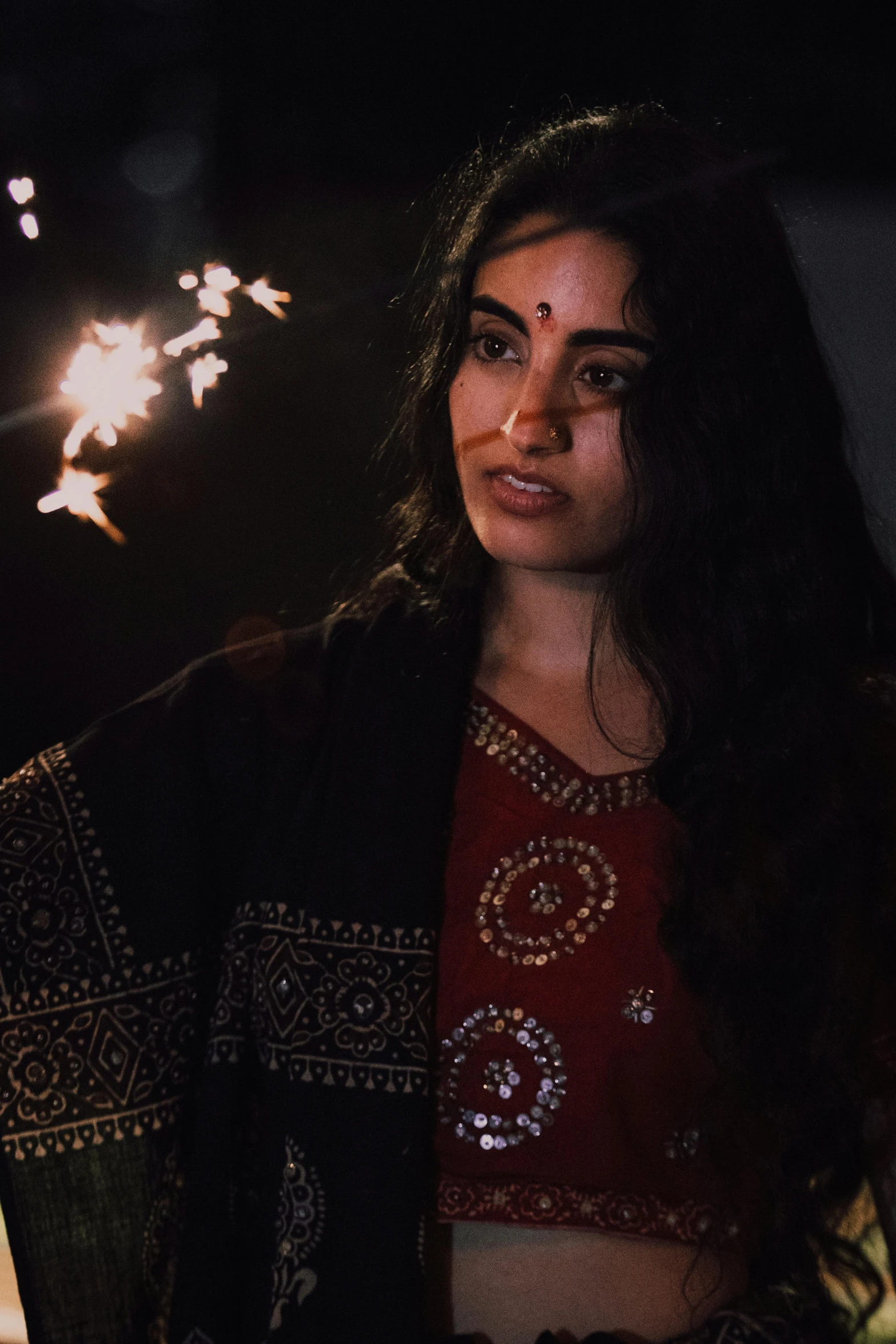 a woman holding sparklers in her hands, an album cover, reddit, dressed in a sari, grainy movie still, **cinematic, official music video