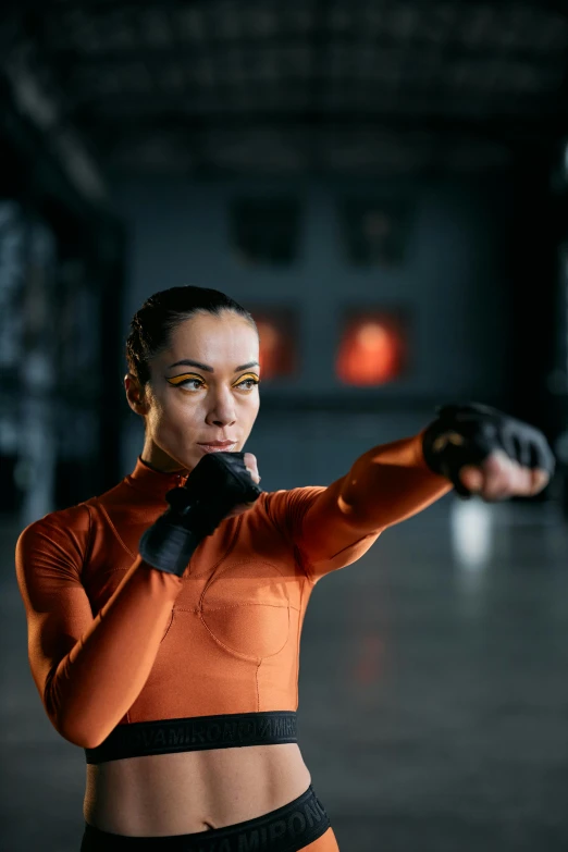 a woman in an orange top and black shorts, inspired by Ma Quan, pexels contest winner, visual art, fighter pose, movie still of cyborg, performance, skintight suits