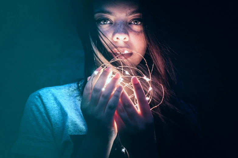 a woman holding a string in front of her face, inspired by Elsa Bleda, pexels contest winner, blue lights and purple lights, teenage girl, instagram post, light tracing