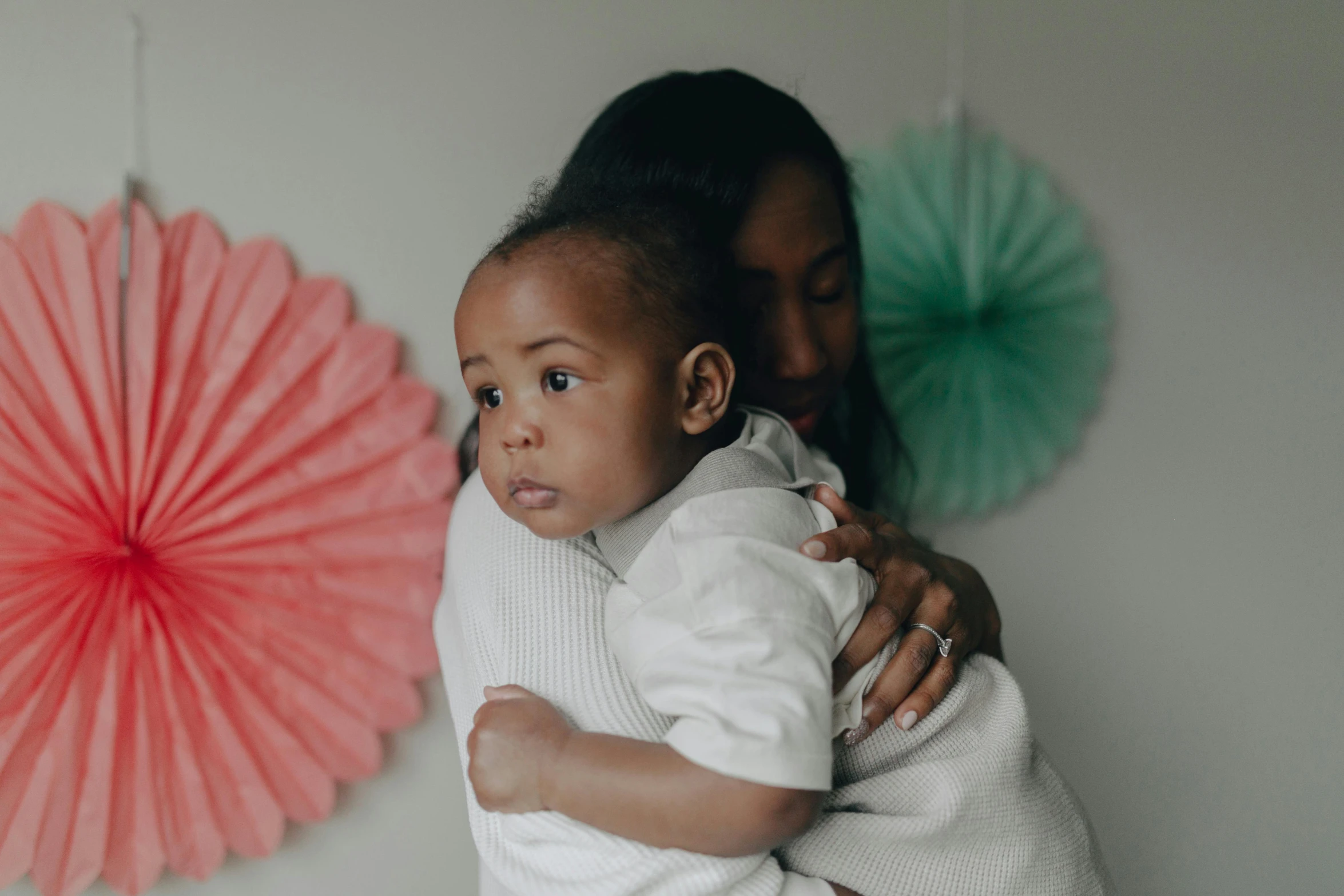 a woman holding a baby in her arms, pexels contest winner, coloured, at home, supportive, backdrop