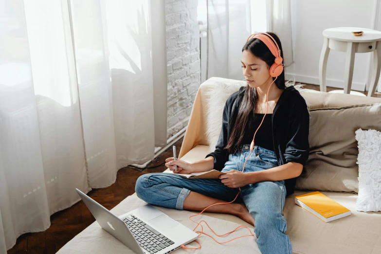 a woman sitting on a couch with a laptop and headphones, by Julia Pishtar, trending on pexels, sitting on the floor, with notes, a young asian woman, student