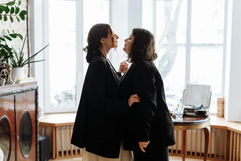 a couple of women standing next to each other, by Julia Pishtar, unsplash, antipodeans, licking out, standing in corner of room, on a wooden desk, brunettes