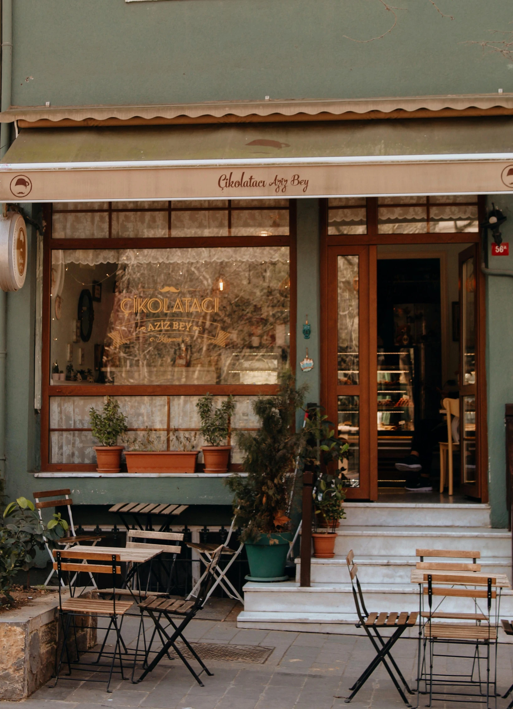 a restaurant with tables and chairs outside of it, by Edward Avedisian, trending on unsplash, art nouveau, at ancinet agora of athens, cute bakery shop, 3/4 front view, chocolate city