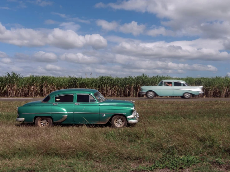 two old cars parked next to each other in a field, a portrait, flickr, cuba, icon, stacked image, medium angle