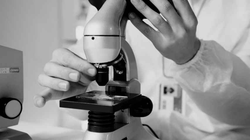 a close up of a person looking through a microscope, by Adam Marczyński, bw photo, medical laboratory, featured, white