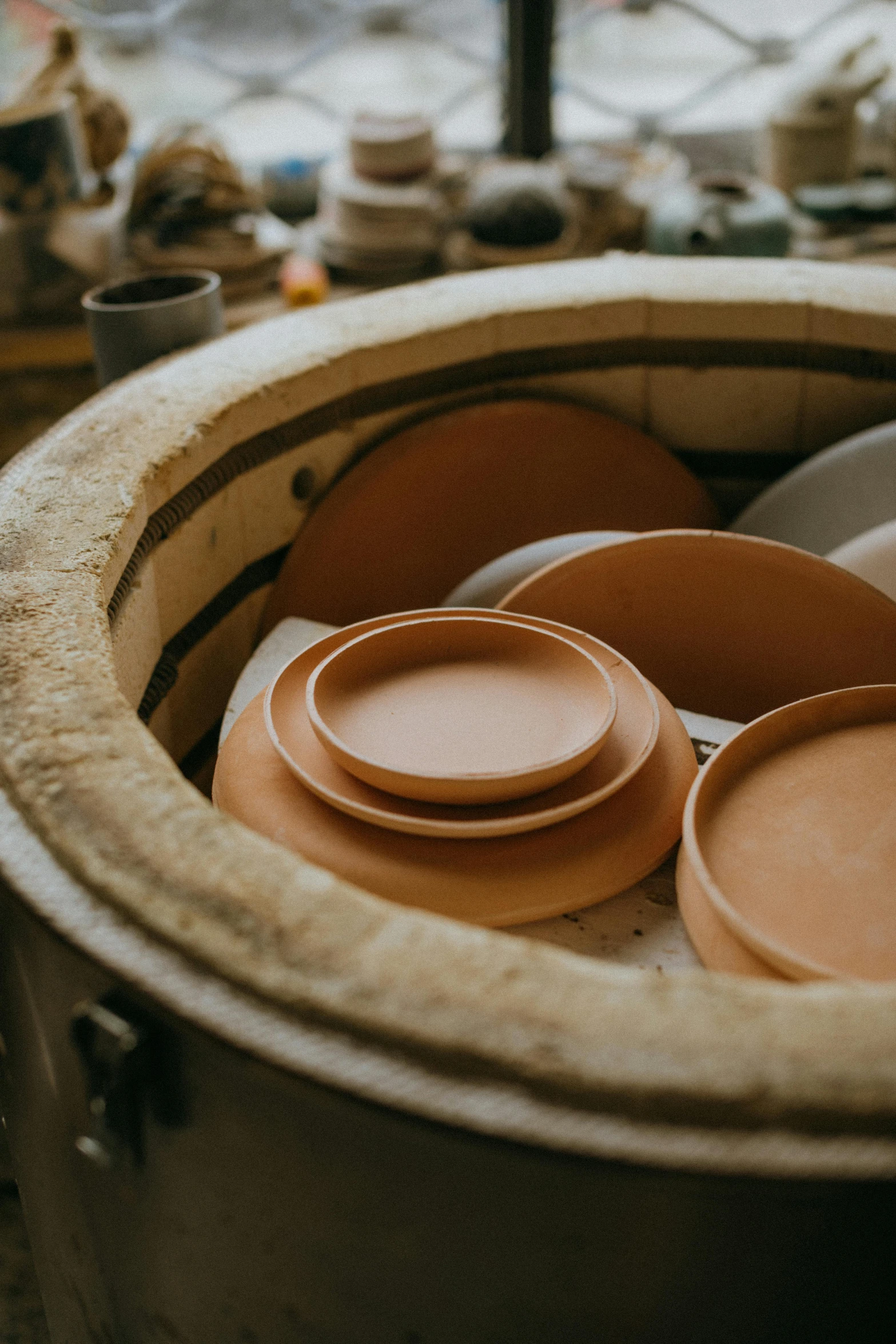 a pot filled with bowls sitting on top of a table, mill, plates, up close, clay material